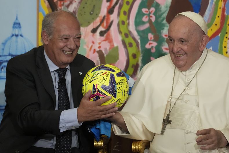 El papa Francisco, acompañado por José María del Corral, presidente de Scholas Occurrentes, sostiene un balón de fútbol que le regalaron en la primera reunión mundial de Ecociudades Educativas, promovida por Scholas Occurrentes, en el Vaticano, 25 de mayo de 2023. (AP Foto/Andrew Medichini)