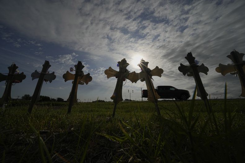 Una camioneta pickup pasa frente a cruces colocadas en memoria a las víctimas de la masacre en la Escuela Primaria Robb en Uvalde, Texas, el miércoles 3 de mayo de 2023. Dos maestras y 19 estudiantes murieron en el tiroteo a mansalva. (AP Foto/Eric Gay)